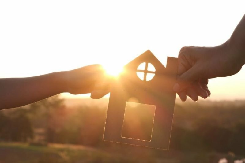 Mother and daughter hands holding paper house, home together silhouette against sunset with soft focus. Concept of Happy Family, Buy House, Home, life, insurance, care, saving, mortgage, estate